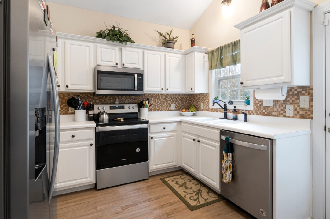 Minimalist kitchen with white cabinets, a scaly backsplash in brown and beige tones.