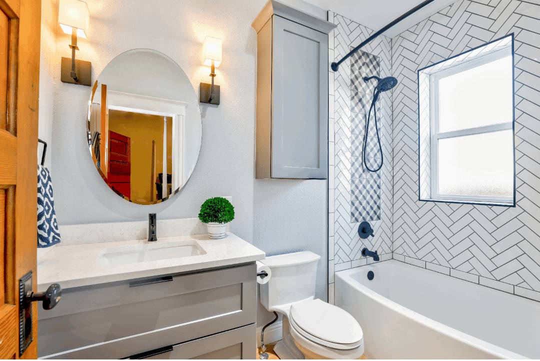 Behind the bathtub is a wall with herringbone subway tiles with black grout