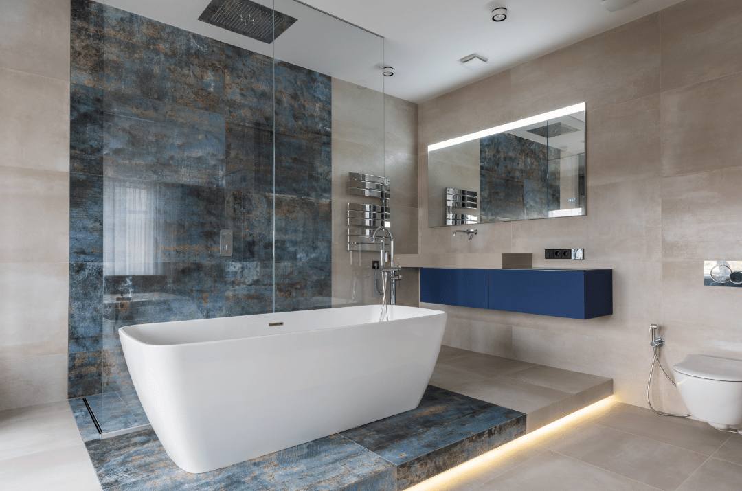 A small bathroom with a white tub and large beige porcelain floor and wall tiles