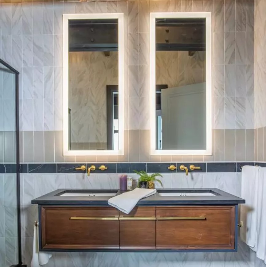 A luxurious bathroom with marble-look wall accents, blending perfectly with the blue sink and rustic drawers.