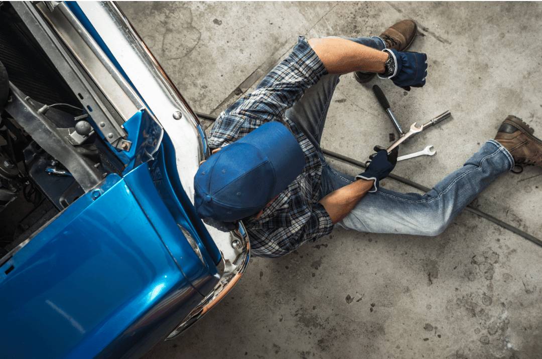 Mechanic sitting on a garage porcelain tile floor