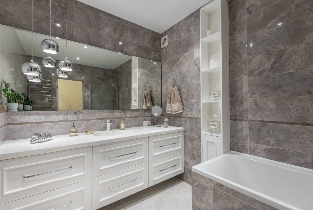 A contemporary bathroom with white cabinets and large gray rectangle porcelain floor and wall tiles.