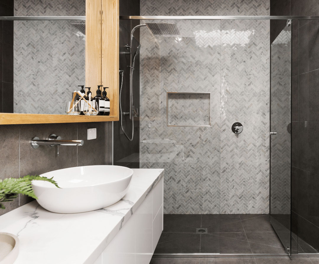 A modern shower room with silver and gray herringbone shower wall tiles