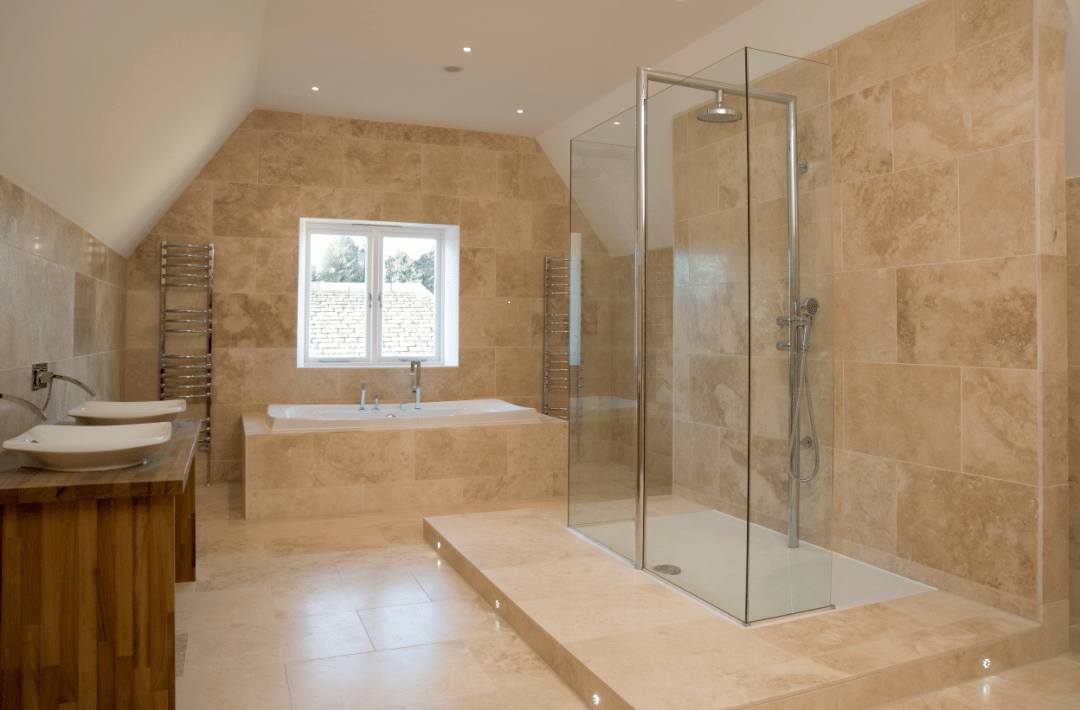 A modern bathroom with a walk-in shower. On its walls and floor are large beige matte porcelain tiles.