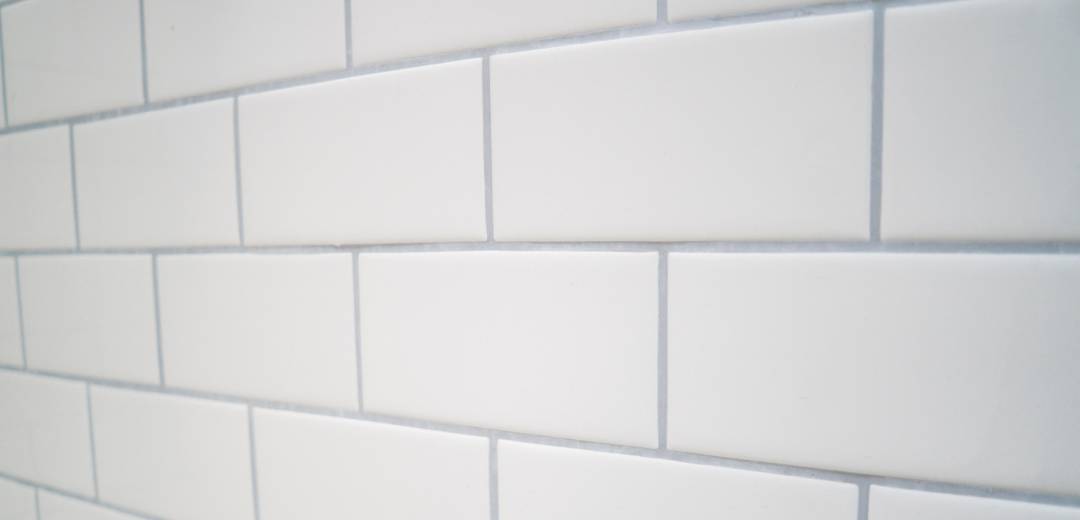 A wall with white subway tiles with gray grouting