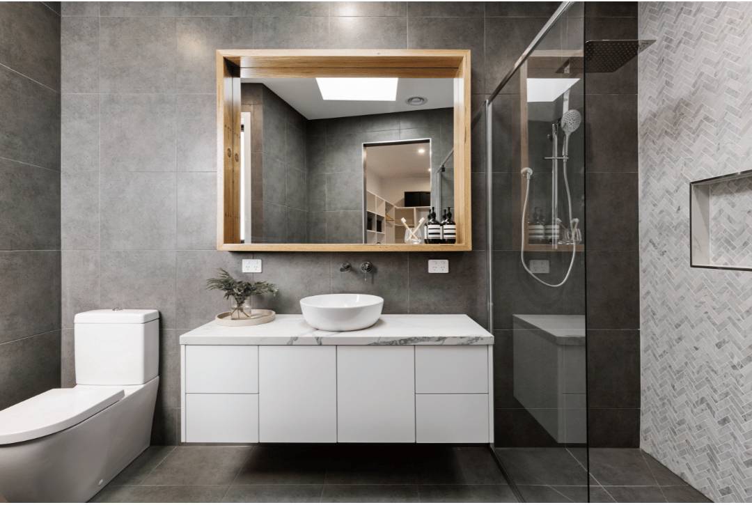 Large gray tile patterns on a modern bathroom. On the left are herringbone tiles on a shower wall