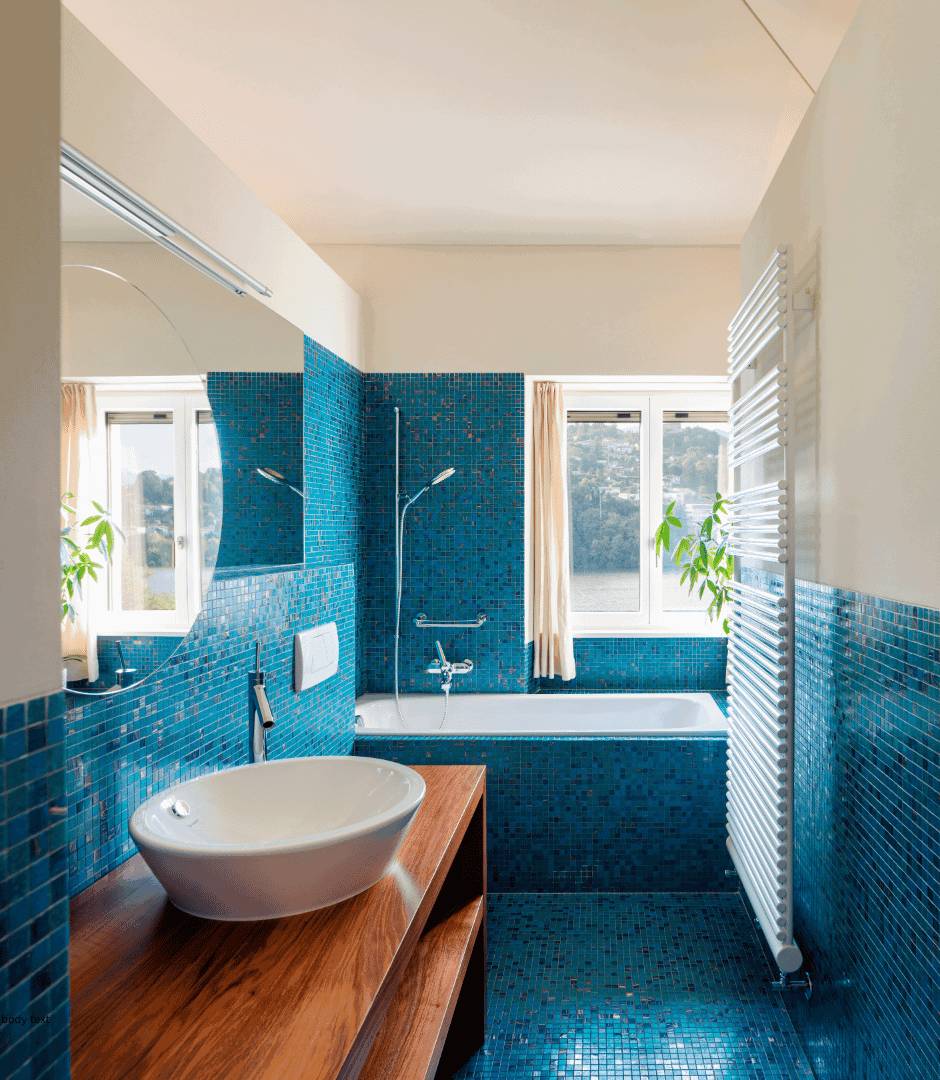 a bathroom and bathtub surrounded with blue and green glass mosaic tiles