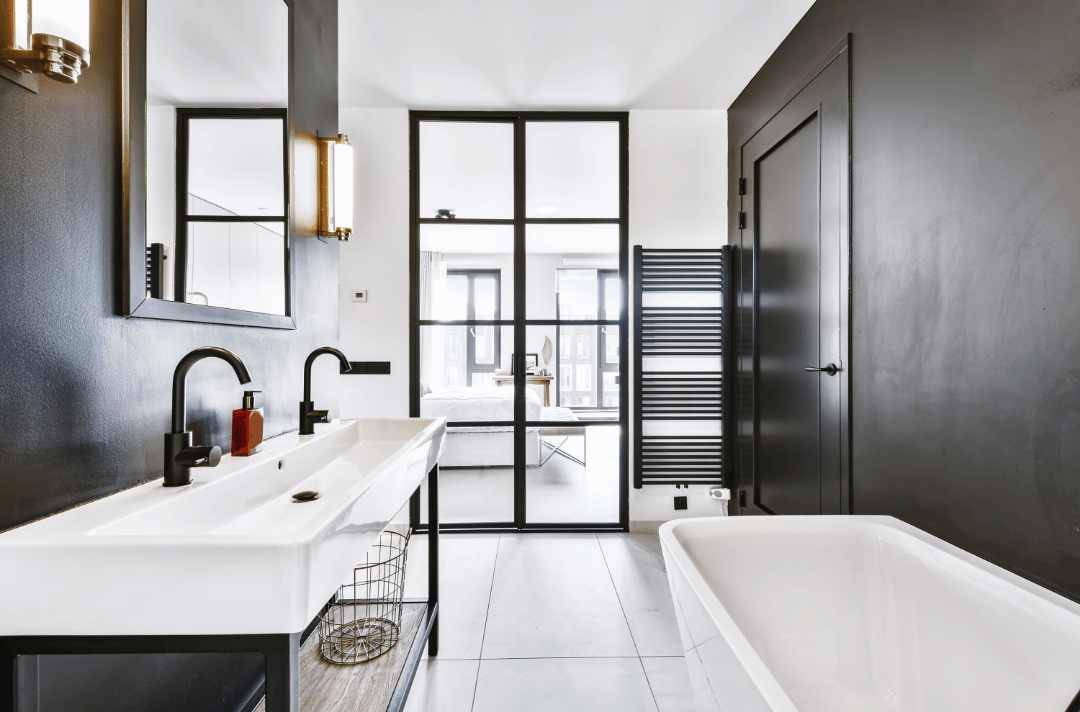 A modern bathroom with large black metallic accent tiles and white large-format floors
