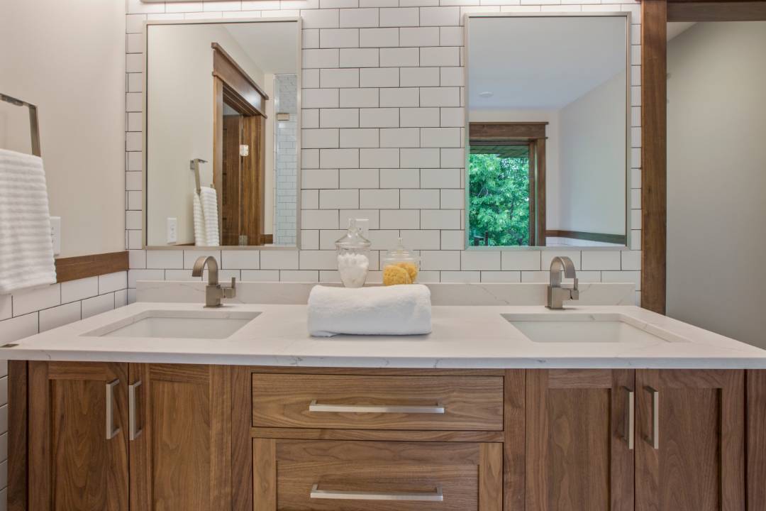 A bathroom wall with white subway tiles and brown grouting