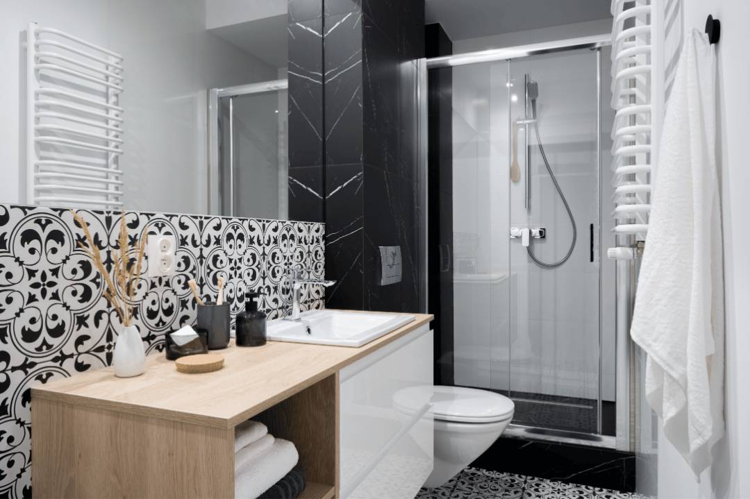 A small bathroom with black and white floral-patterned walls and floors