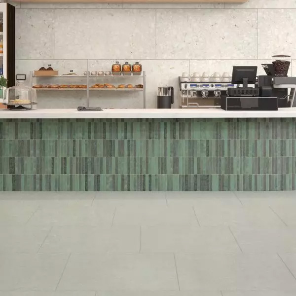 A modern kitchen featuring a stunning backsplash of large rectangular tiles that resemble concrete. These 24x48 Glacier Rectangle Concrete Look Porcelain Tiles create a sleek contrast with the green and gray mosaic countertop trim.