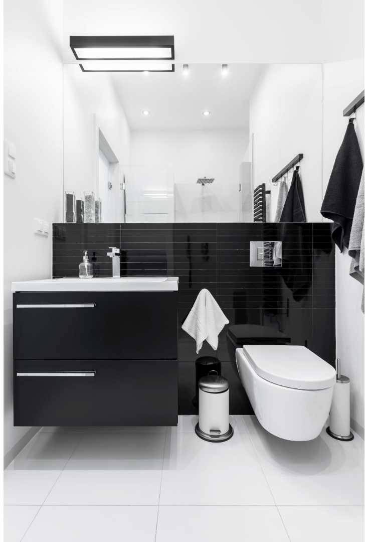 Small bathroom with large white porcelain tile floors and black subway accent tiles