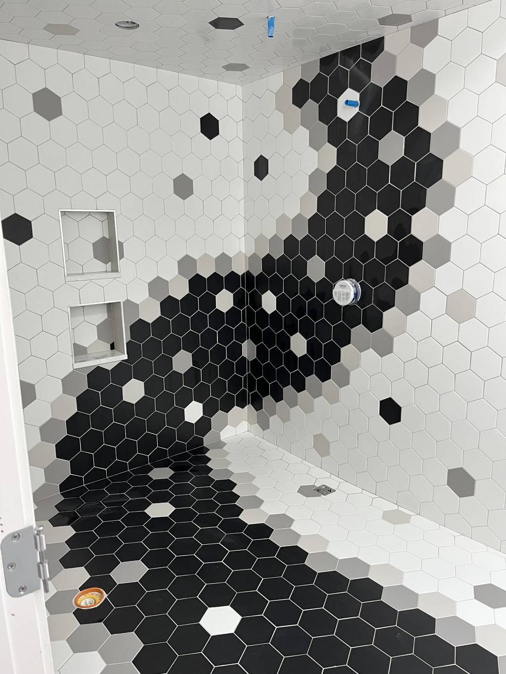A bathroom floor and wall with mixed color designs using hexagon tiles