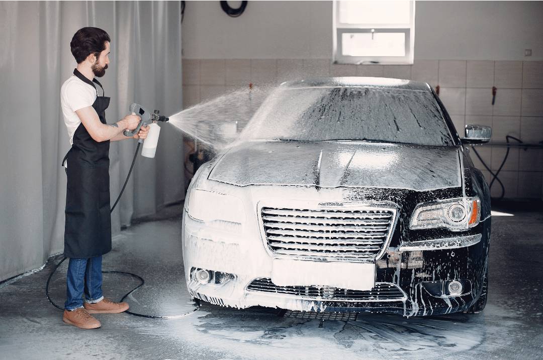 man washing his car inside his garage