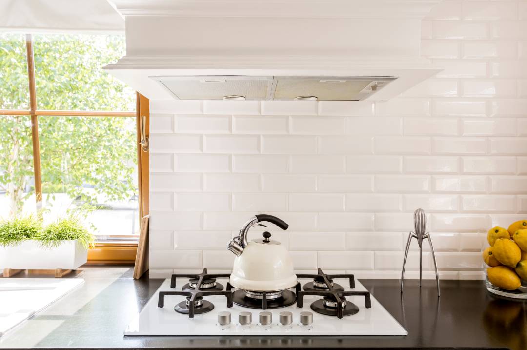 A traditional kitchen with a black cooktop and white subway backsplash tiles. The subways tiles have almost invisible white grouting.